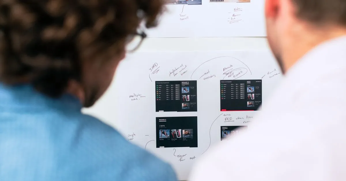 Two business professionals brainstorming and planning software development with a whiteboard in an office.