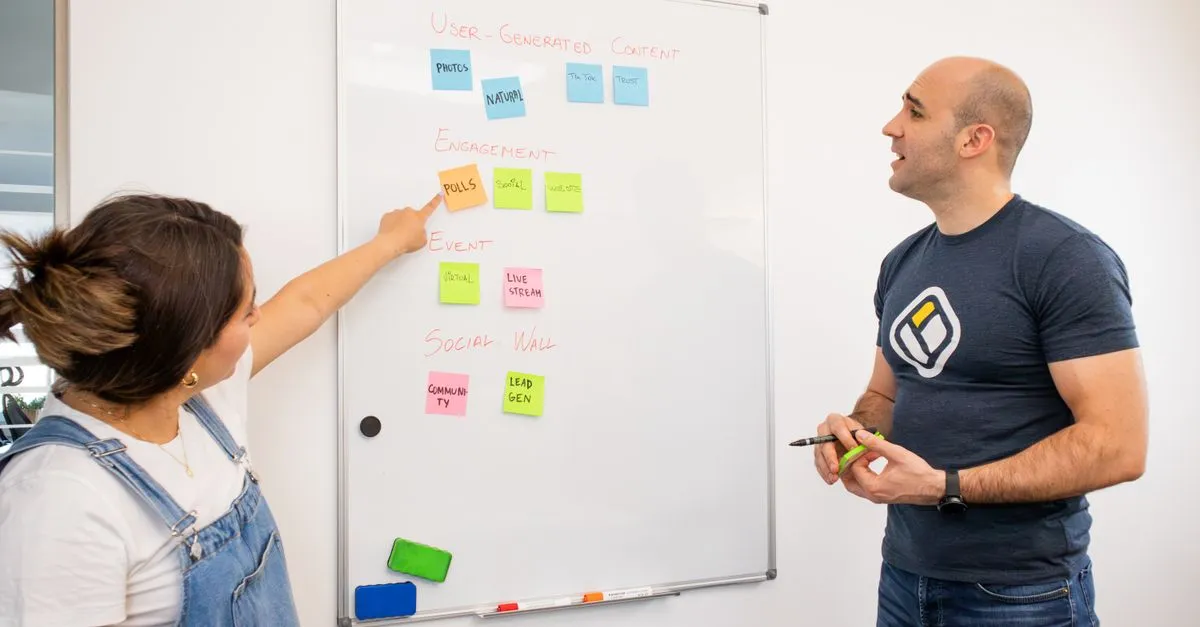 Two colleagues brainstorm on a whiteboard with colorful sticky notes for project planning.