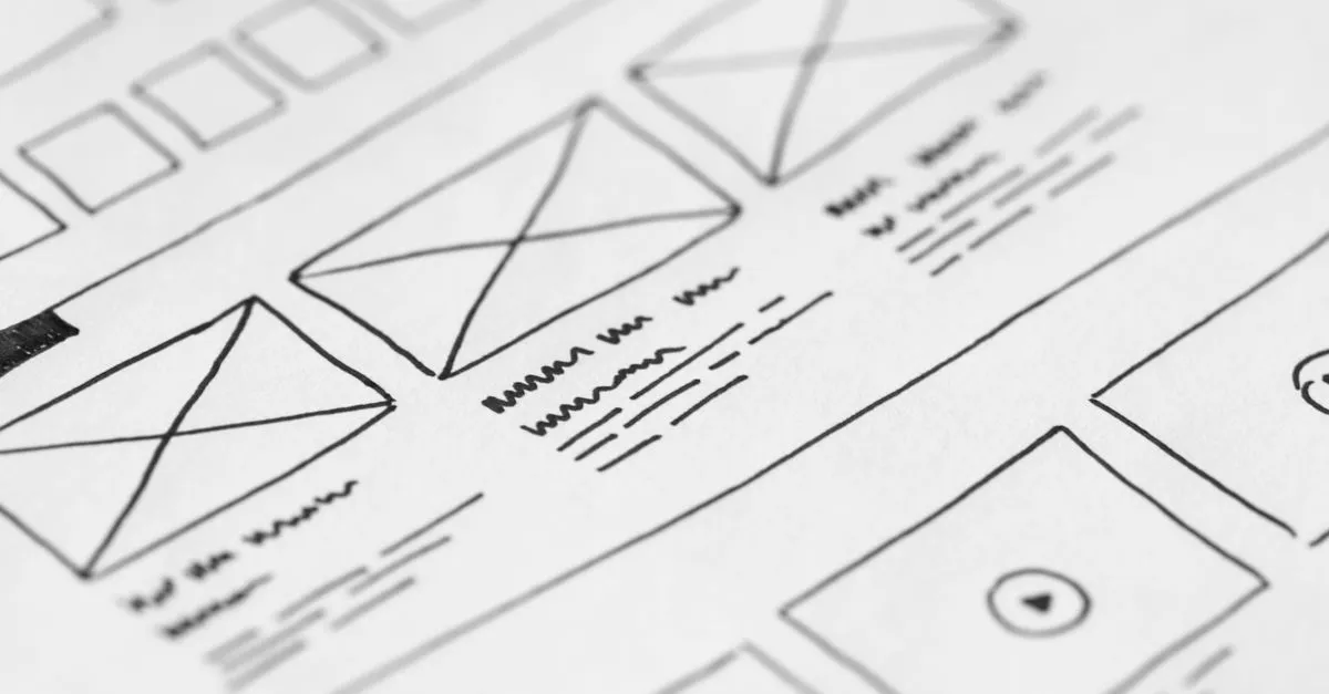 Designér skicuje nový návrh webu vedle obrazovky