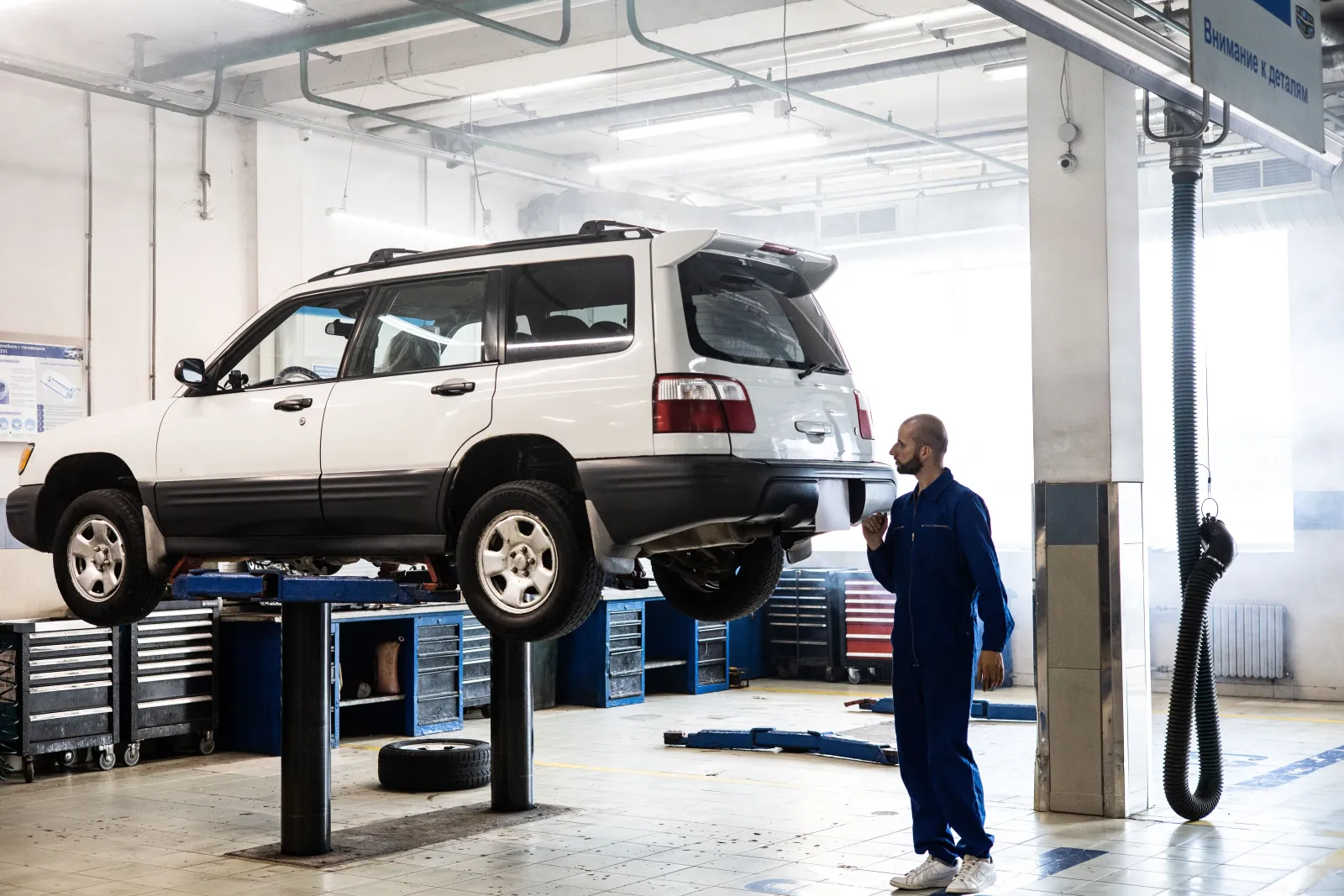 Moderní autoservis s vozem na zvedáku a mechanikem